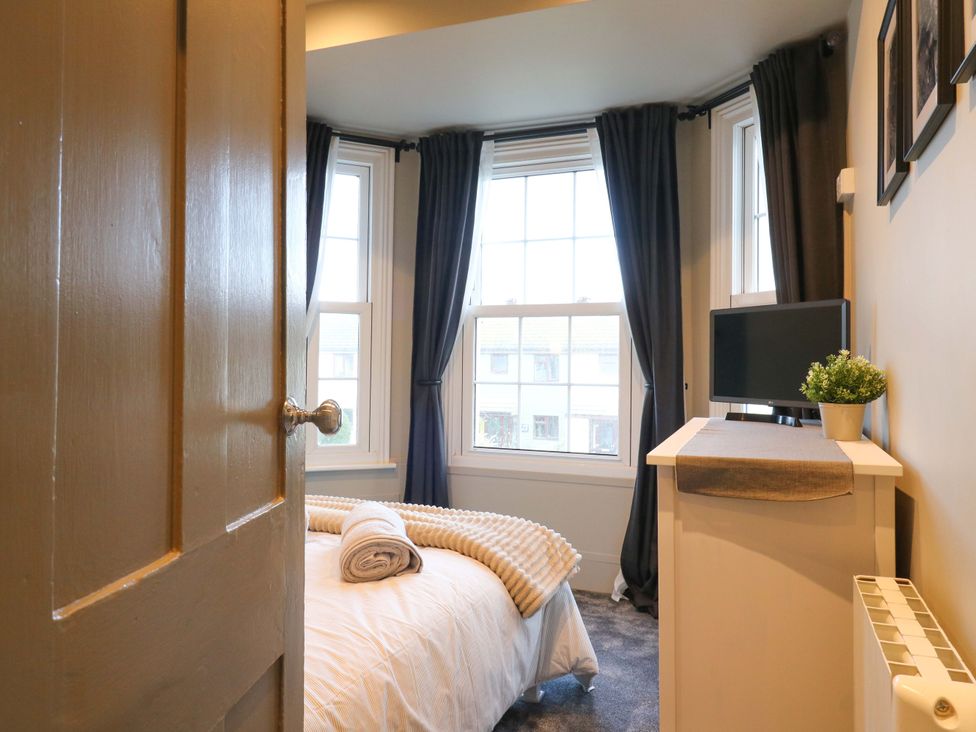 A bedroom with a bed and television at 1A Coastguard Cottages in Rye