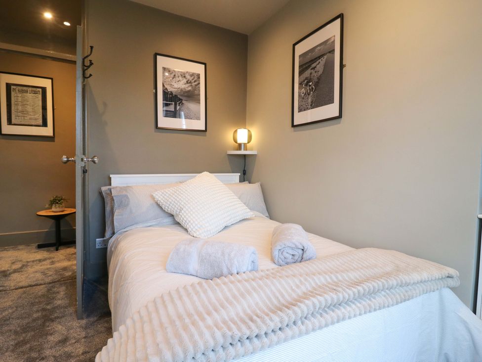 A bedroom with a bed and wall art at 1A Coastguard Cottages in Rye