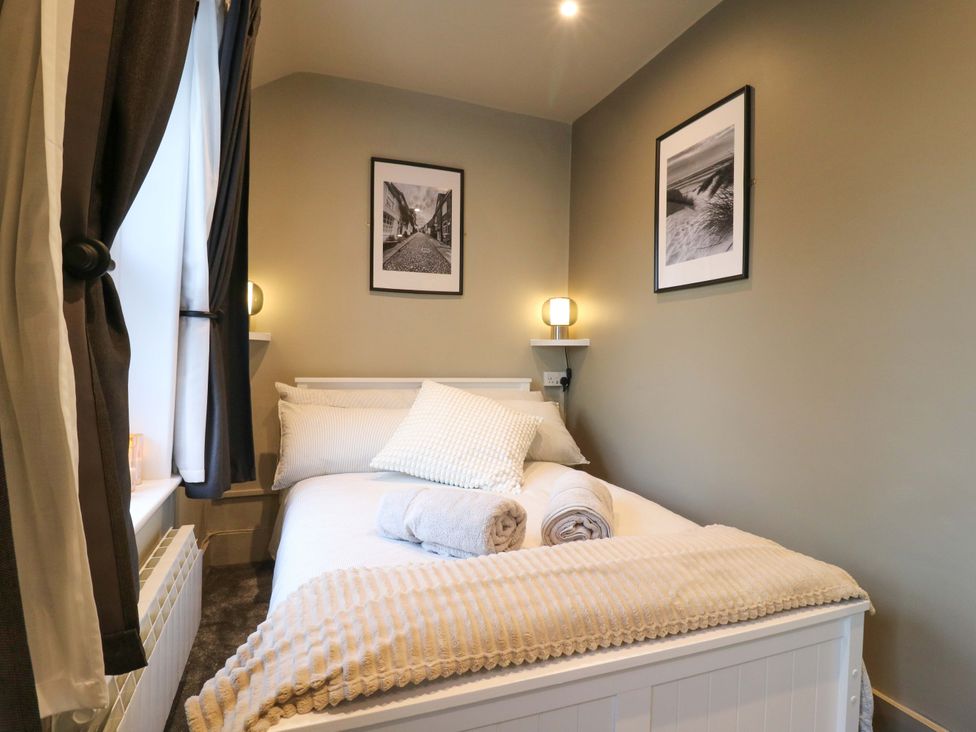 A bedroom with a bed and wall art at 1A Coastguard Cottages in Rye
