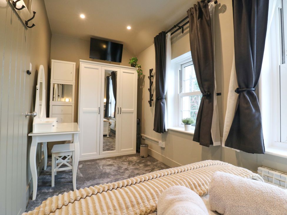A bedroom with a bed, wardrobe, and desk at 1A Coastguard Cottages in Rye