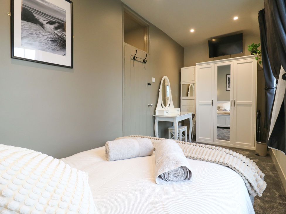 A bedroom with a bed, dresser, wardrobe and television at 1A Coastguard Cottages in Rye