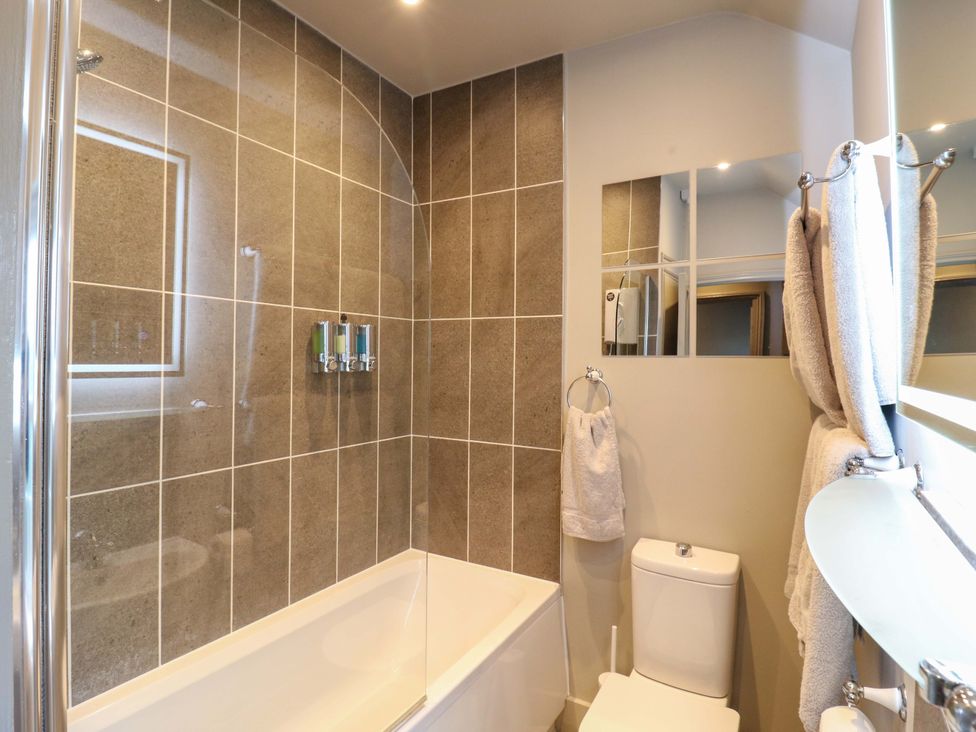 A bathroom with a bathtub and shower at 1A Coastguard Cottages in Rye