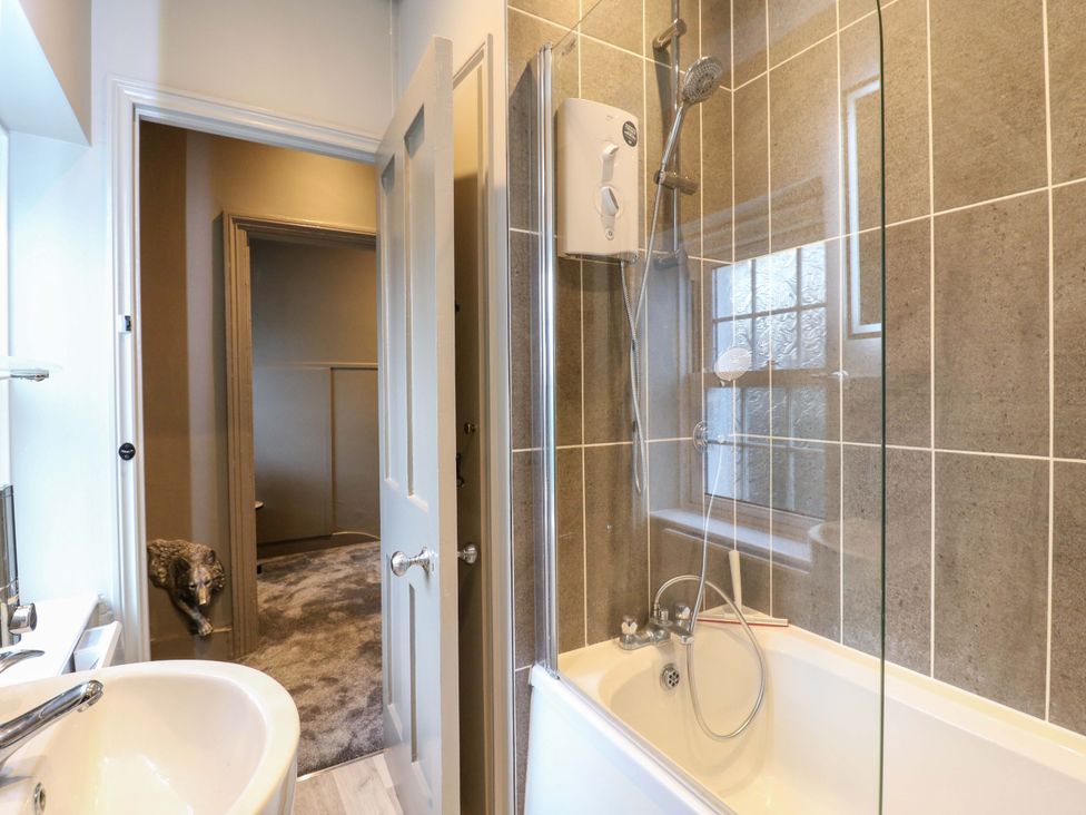 A bathroom with a bathtub and shower at 1A Coastguard Cottages in Rye