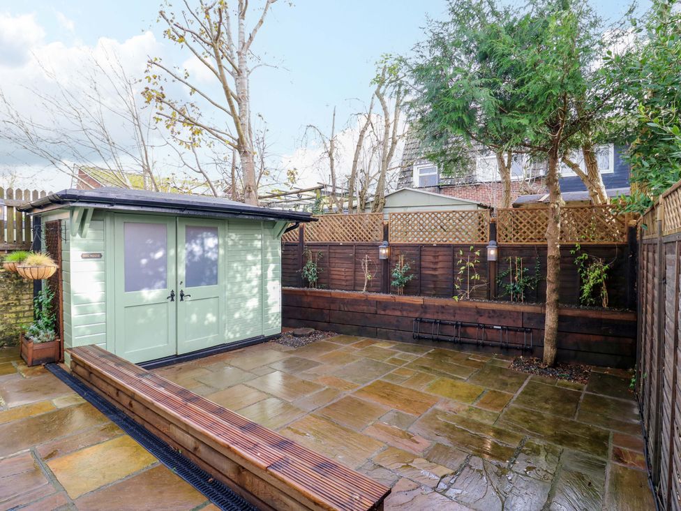 A garden with a shed, paving stones, and planters at 1A Coastguard Cottages Rye