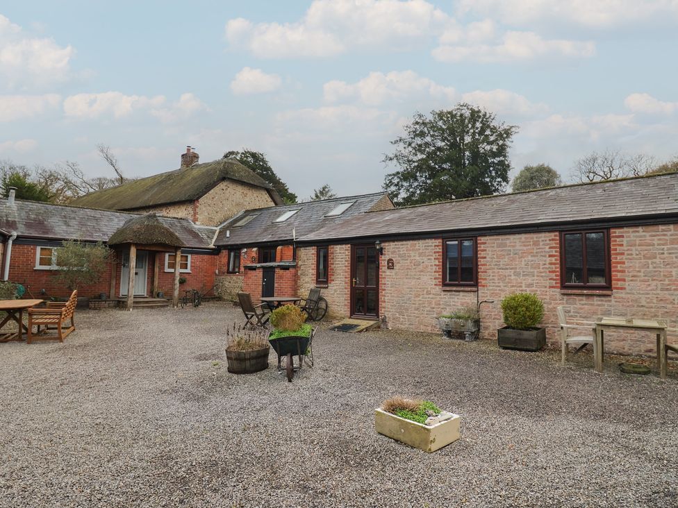 An outdoor area with a cottage, gravel, table and chairs at Apple Cottage in Whitchurch Canonicorum