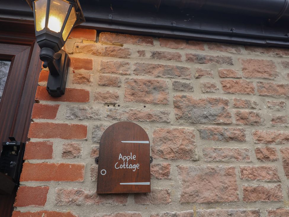 A sign displaying the name Apple Cottage on a brick wall at Apple Cottage in Whitchurch Canonicorum
