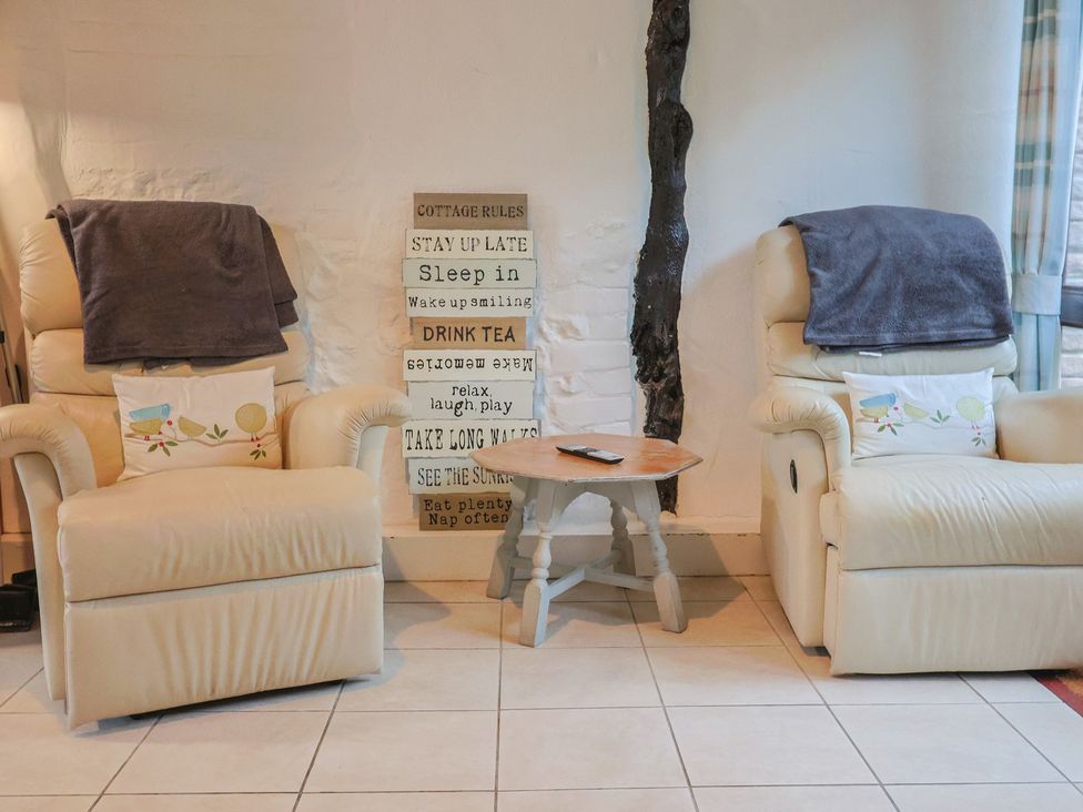 A living room with recliner chairs and a decorative sign at Apple Cottage in Whitchurch Canonicorum