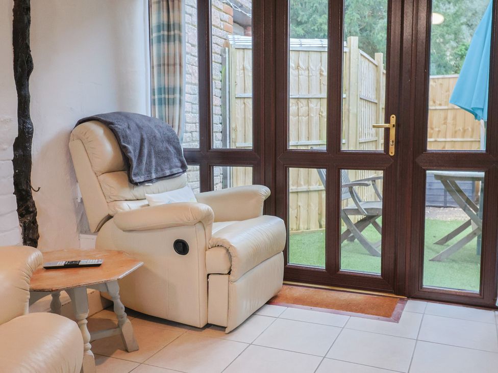A living room with an armchair and sliding door to outdoor area at Apple Cottage Whitchurch Canonicorum