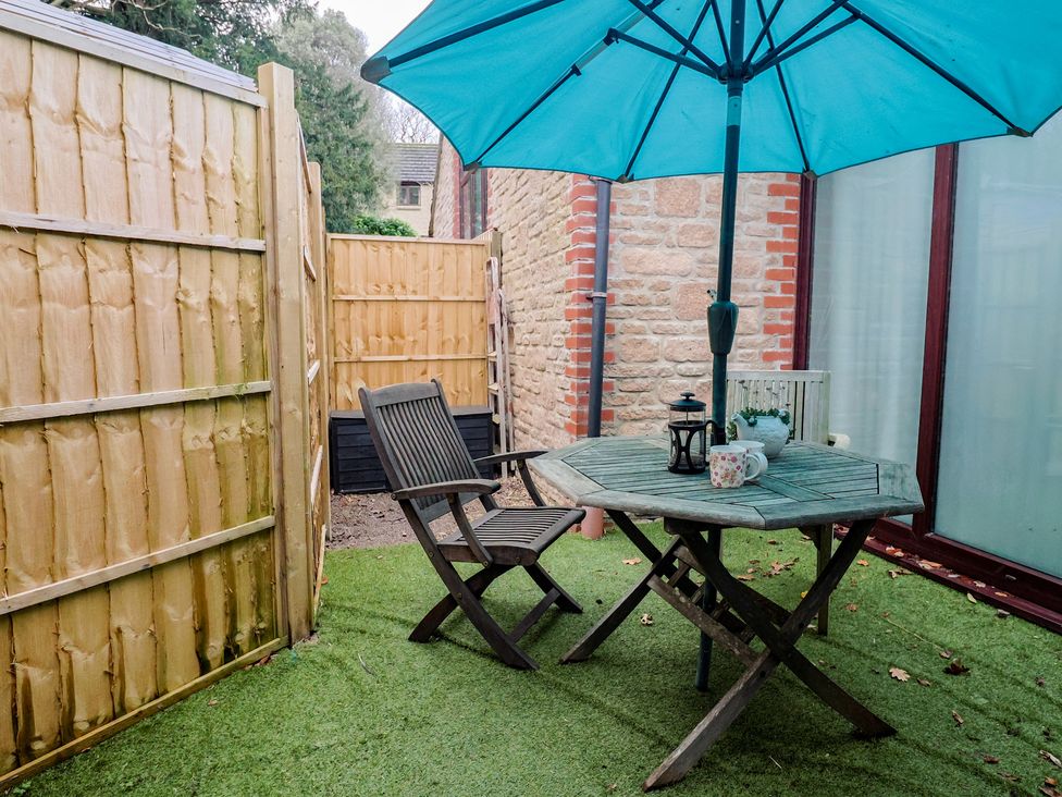 A garden with a table and chair under an umbrella at Apple Cottage Whitchurch Canonicorum