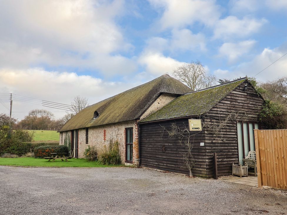 A building with a thatched roof and wooden structure at Apple Cottage Whitchurch Canonicorum