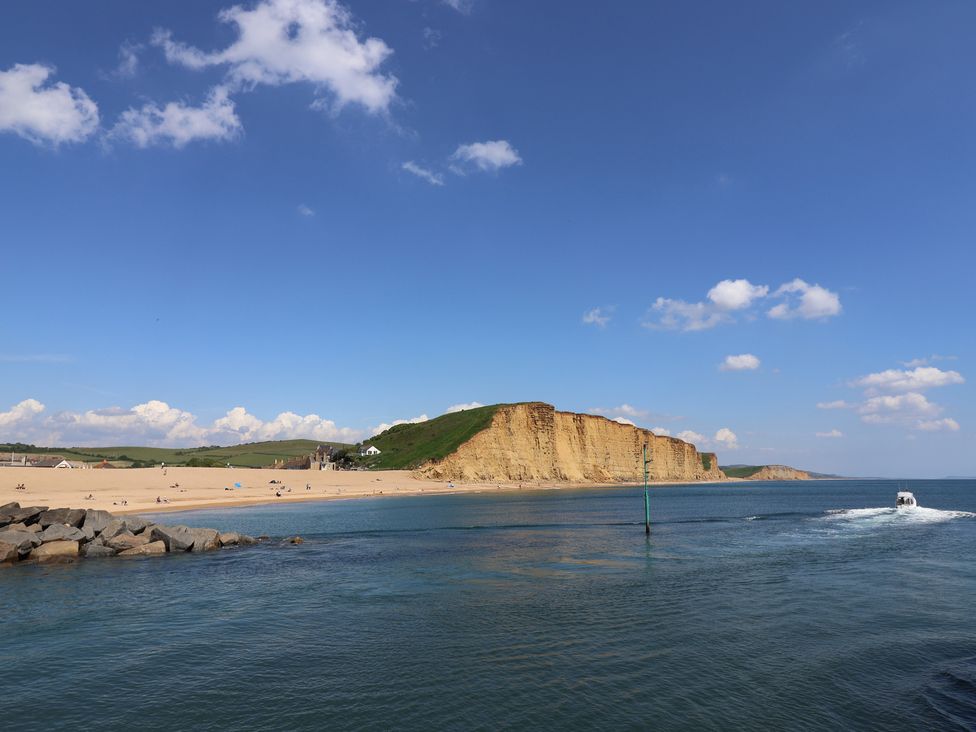 A beach with cliffs and a boat on the sea at Apple Cottage in Whitchurch Canonicorum
