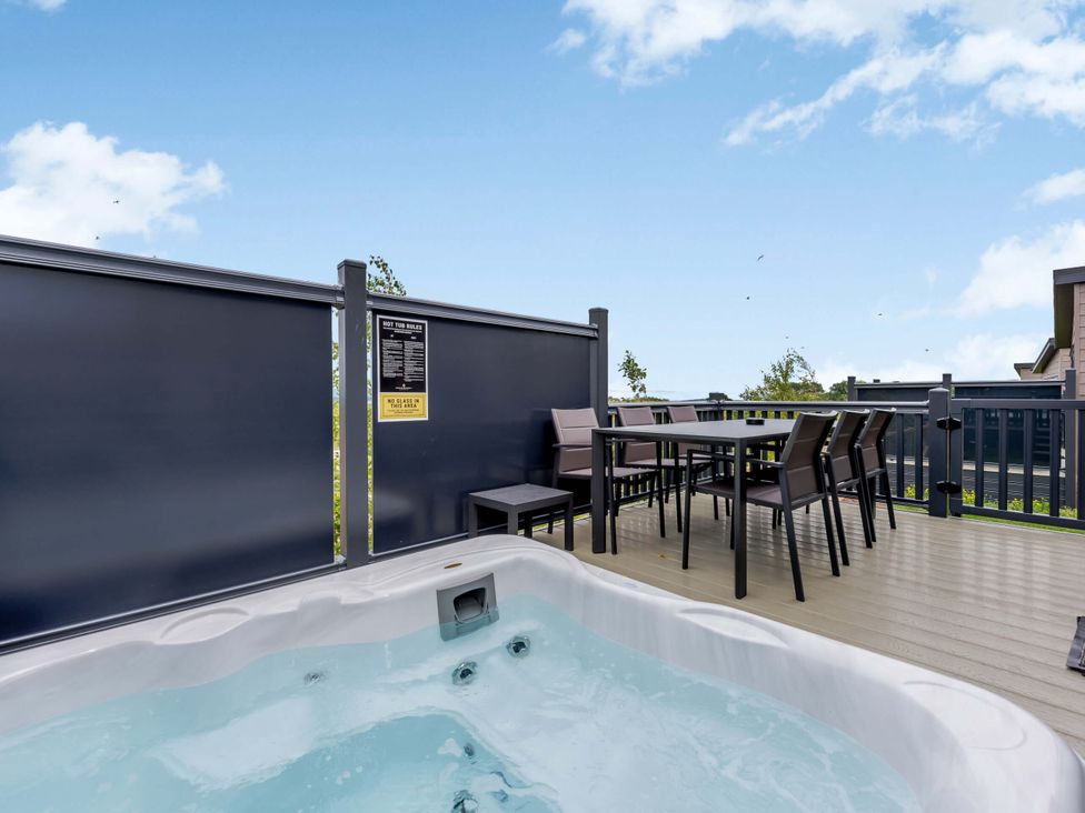 An outdoor area with a hot tub and dining table at Blencathra Family (Pet) in Penrith