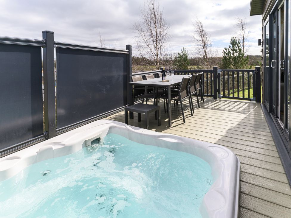 An outdoor area with a hot tub and a dining set at Blencathra Family (Pet) in Penrith