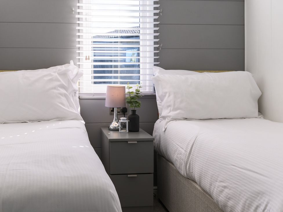 A bedroom with two beds and a nightstand at Blencathra Family (Pet) in Penrith