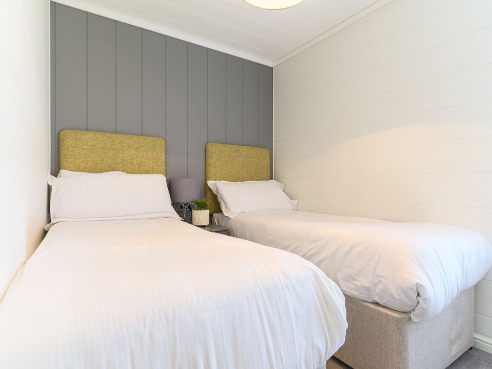 A bedroom with two beds and a bedside table at Grasmere in Penrith