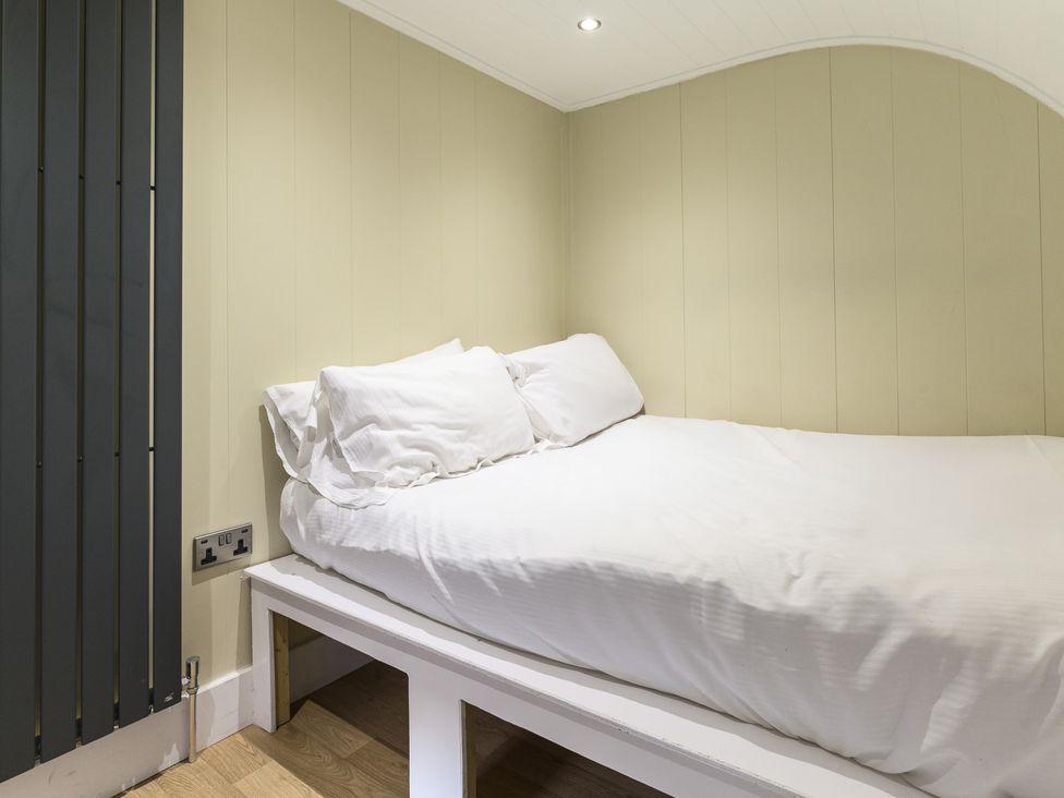 A bedroom with a bed and headboard at Pods by the Lake in Penrith