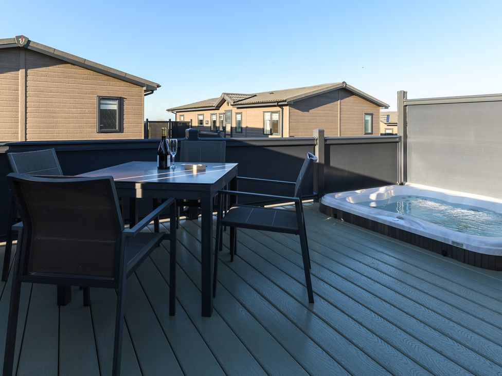 An outdoor area with a table and chairs and a hot tub at Grasmere (Pet) Penrith