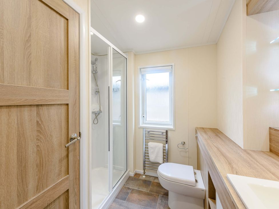 A bathroom with shower, sink, toilet, and towel rail at Keswick (Pet) Penrith