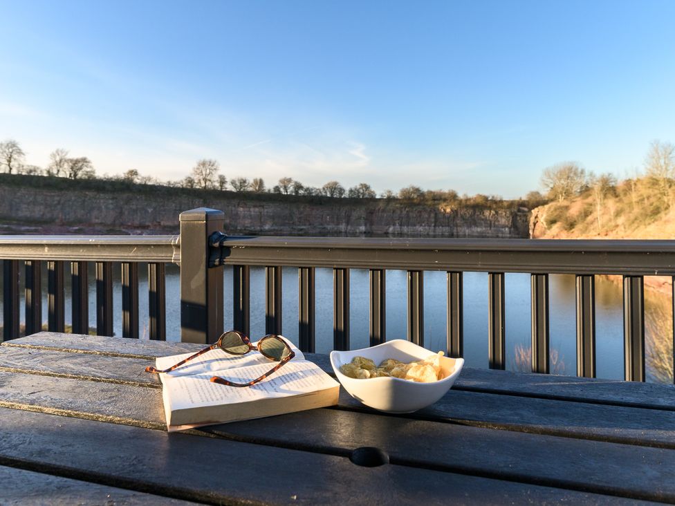 A table with a book, sunglasses, and a bowl of snacks at Pods by the Lake (Pet) Penrith