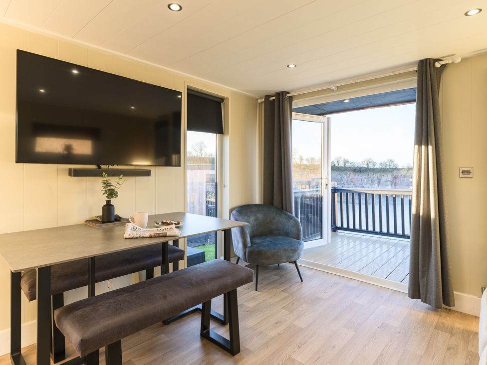 A living room with a television and dining area at Pods by the Lake (Pet) Penrith