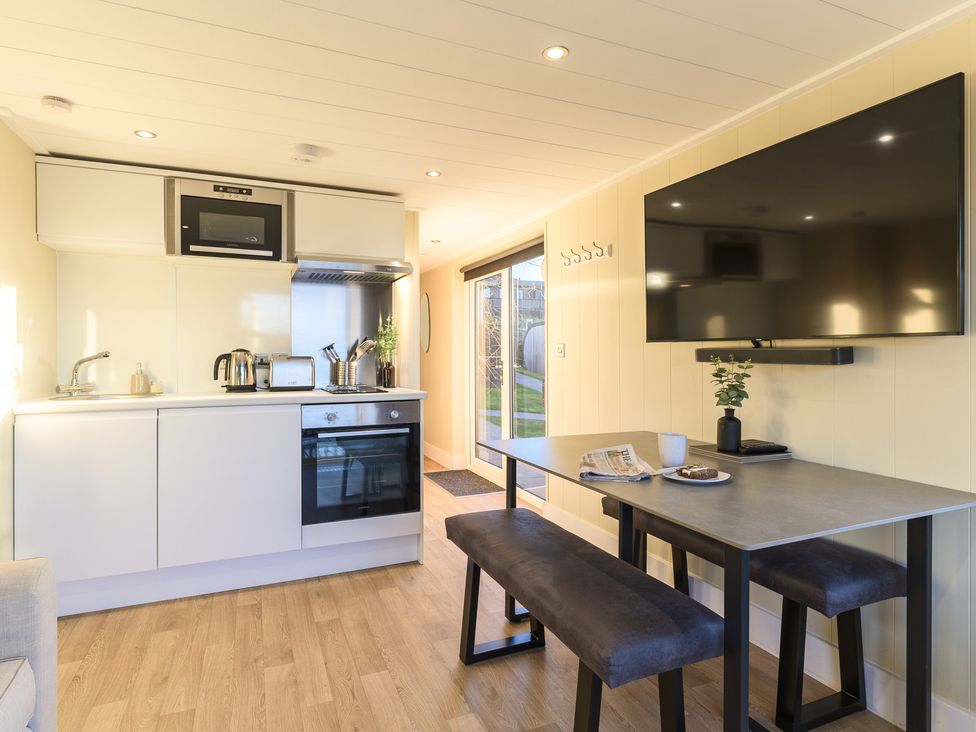 A kitchen with appliances and a dining area at Pods by the Lake (Pet) Penrith