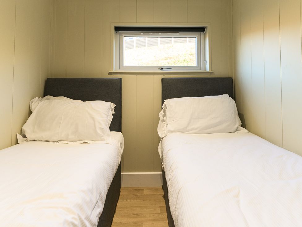 A bedroom with two single beds near a window at Pods by the Lake (Pet) Penrith