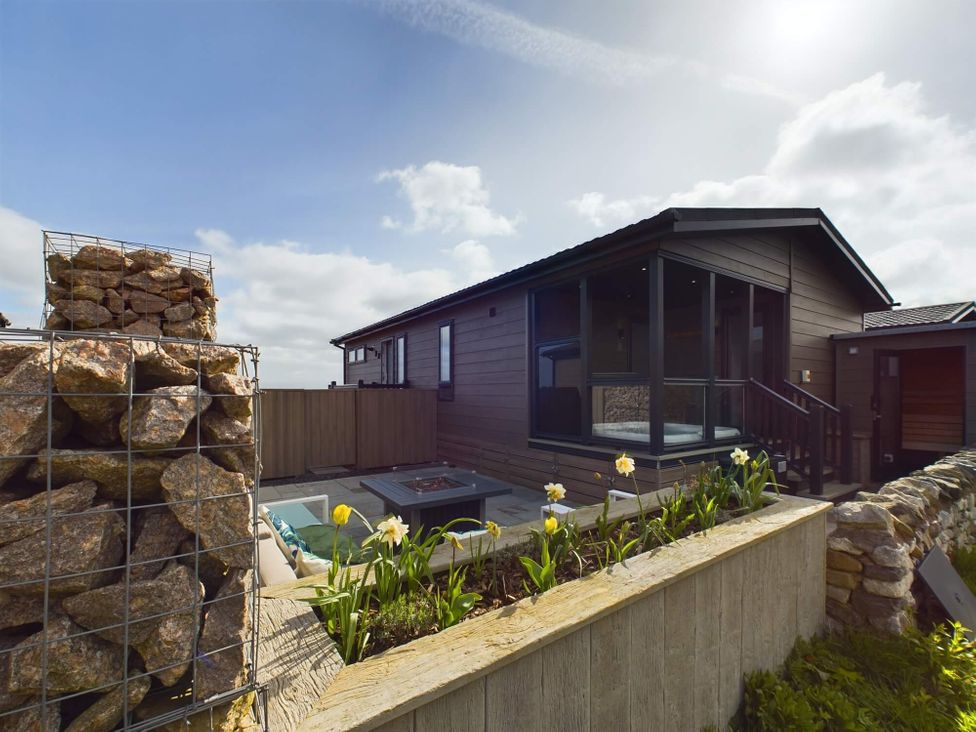 An outdoor area with a house, flowers, and a fire pit at Spa Sauna Lodge, Penrith