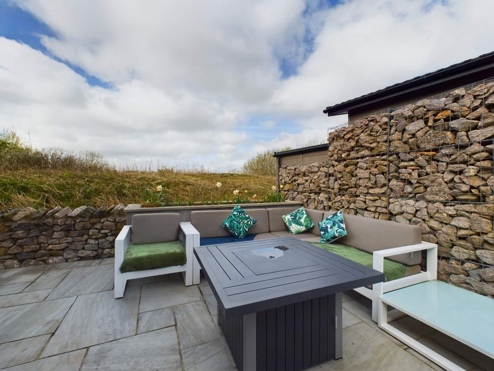 An outdoor seating area with a stone wall and a coffee table at Spa Sauna Lodge in Penrith