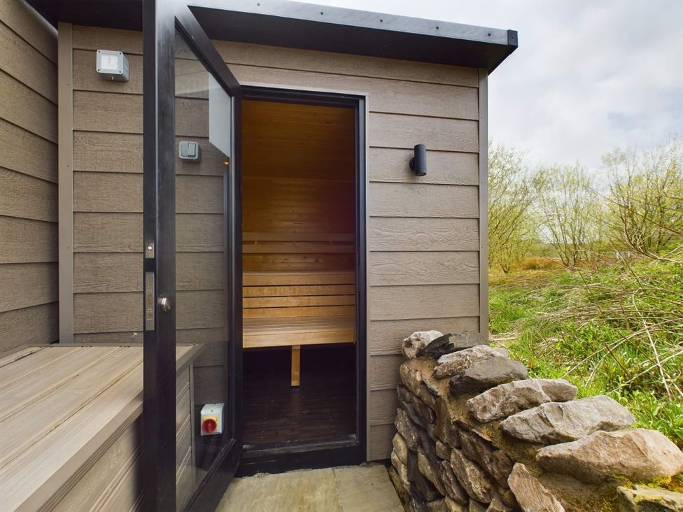 A sauna entrance with bench and stone wall at Spa Sauna Lodge (Pet) Penrith