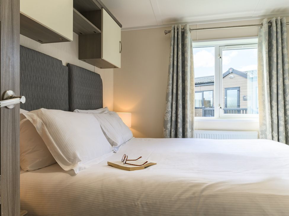 A bedroom with a bed, shelves and curtains at Helvellyn (Pet) in Penrith