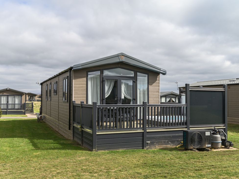 A holiday home with a deck and grass area at Blencathra Spa (Pet) Penrith