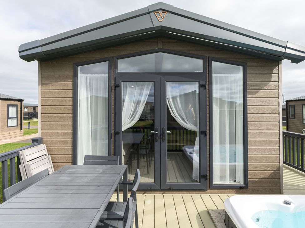 An outdoor space with a table and chairs near a jacuzzi at Blencathra Spa (Pet) Penrith
