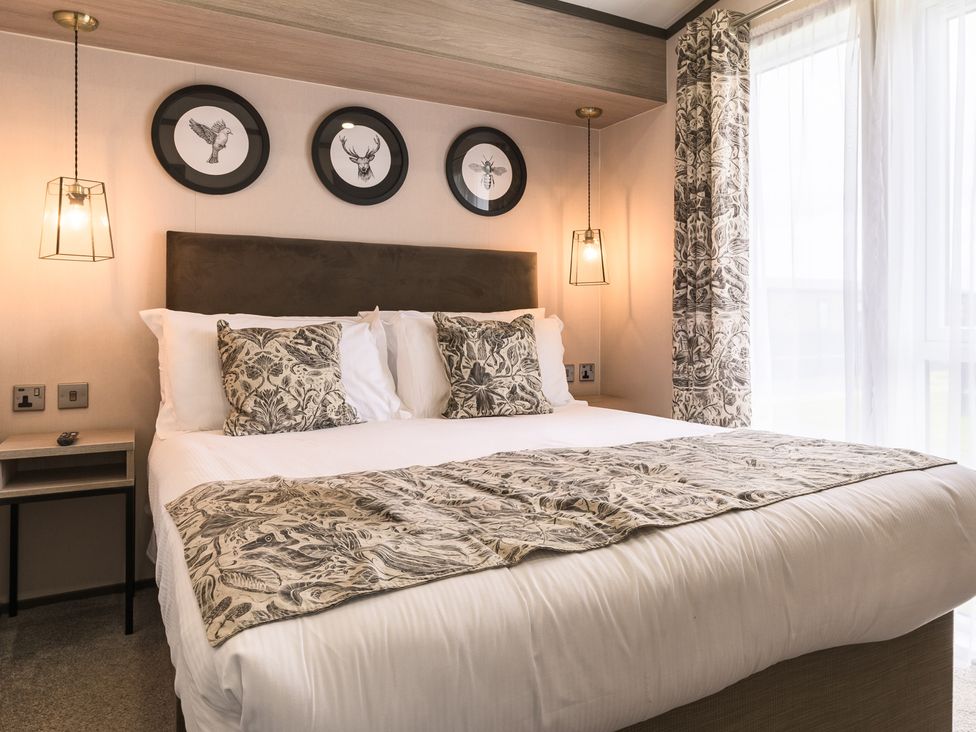 A bedroom with a bed, bedside table, and decorative wall art at Blencathra Spa (Pet) in Penrith