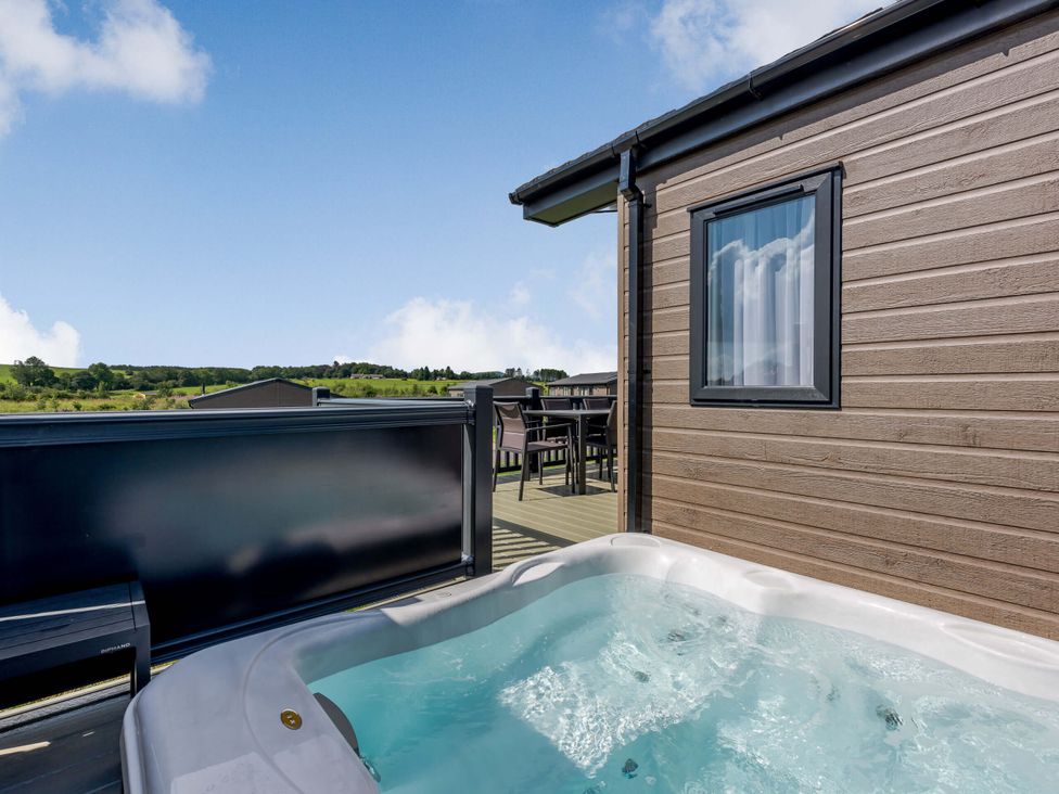 An outdoor area with a hot tub and seating at Scaféll (Pet) in Penrith