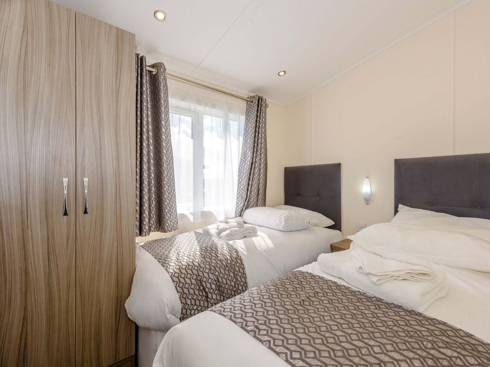 A bedroom with two beds and a wardrobe at Scaféll (Pet) in Penrith