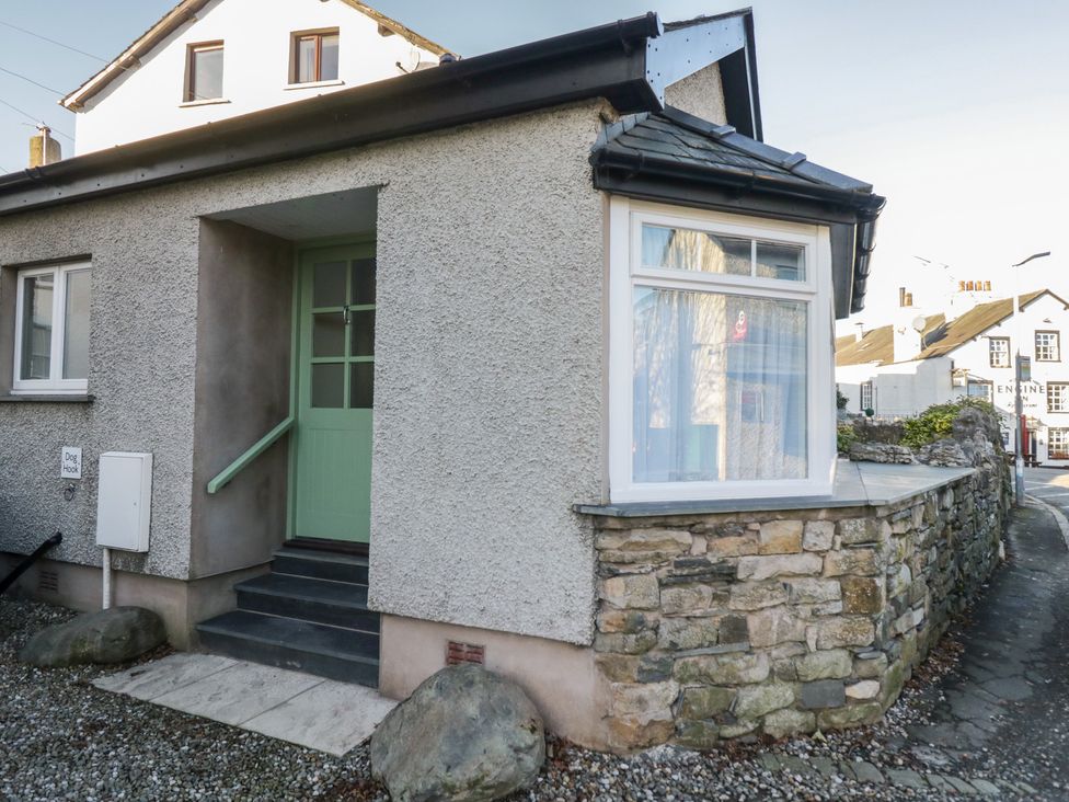 An exterior view of a house with a green door and stone wall at Renes Shop in Grange-Over-Sands