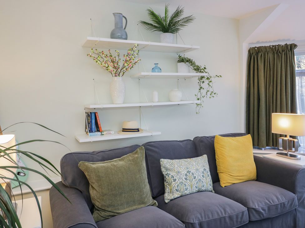 A living room with a sofa and shelves holding decorative items at Renes Shop in Grange-Over-Sands