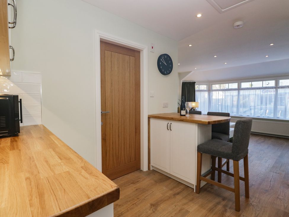A kitchen with a bar counter and clock at Renes Shop in Grange-Over-Sands