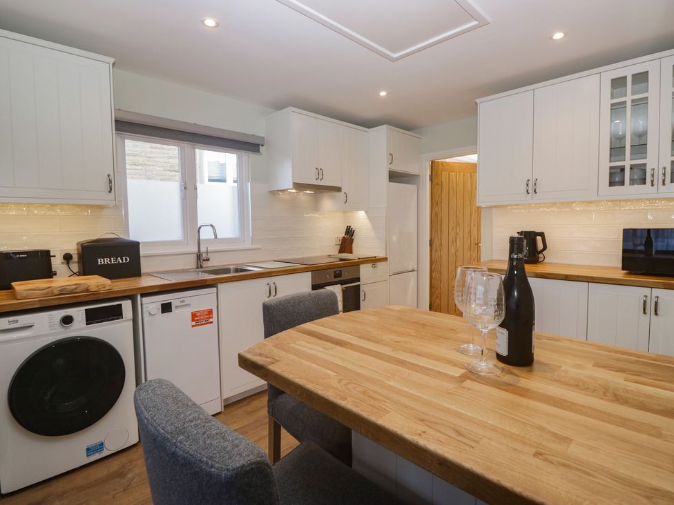 A kitchen with wooden table and appliances at Renes Shop in Grange-Over-Sands
