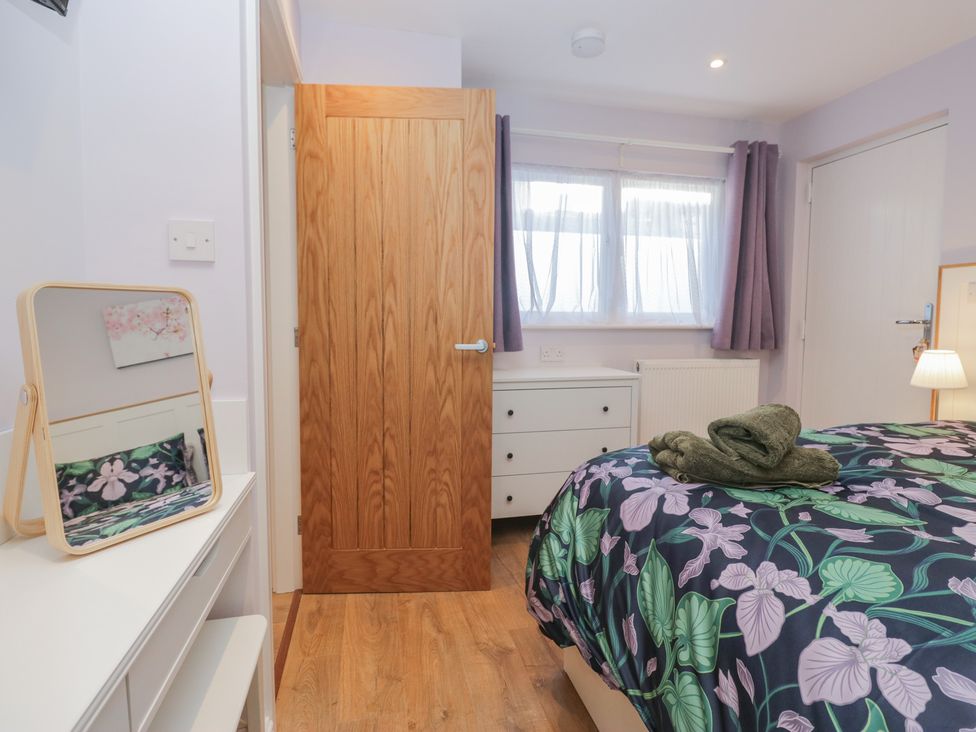 A bedroom with a bed and mirror at Renes Shop Grange-Over-Sands