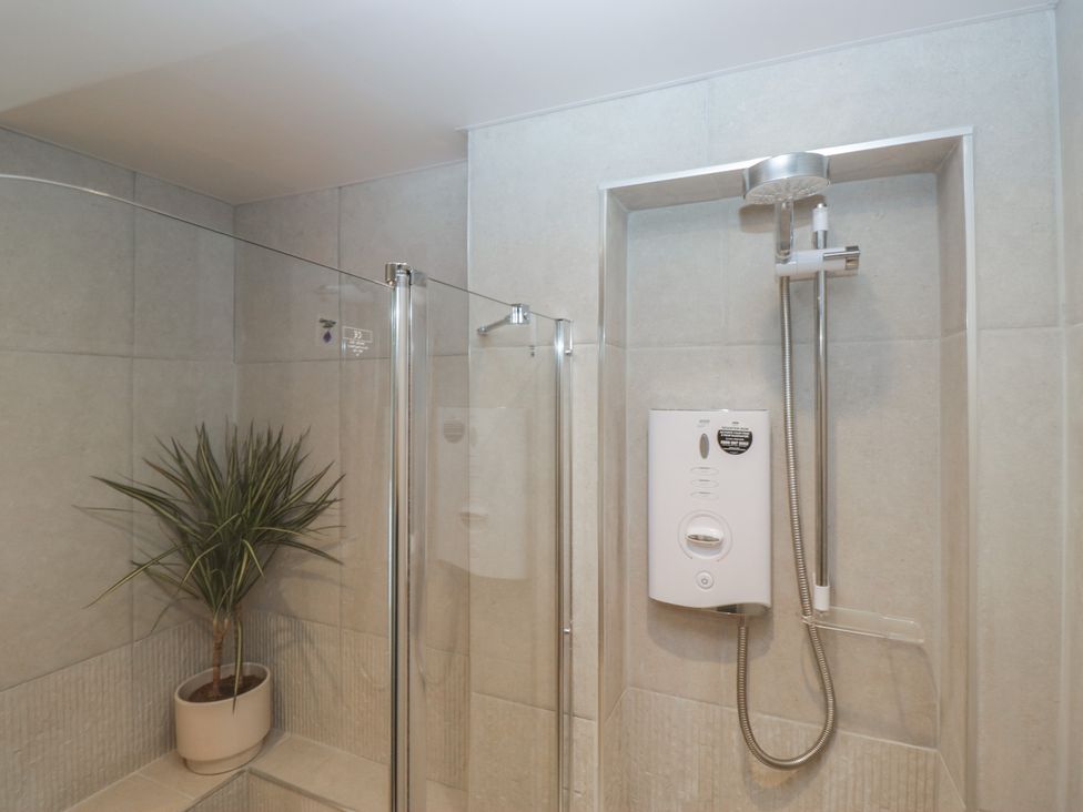A shower with a showerhead and control panel in a bathroom at Renes Shop Grange-Over-Sands