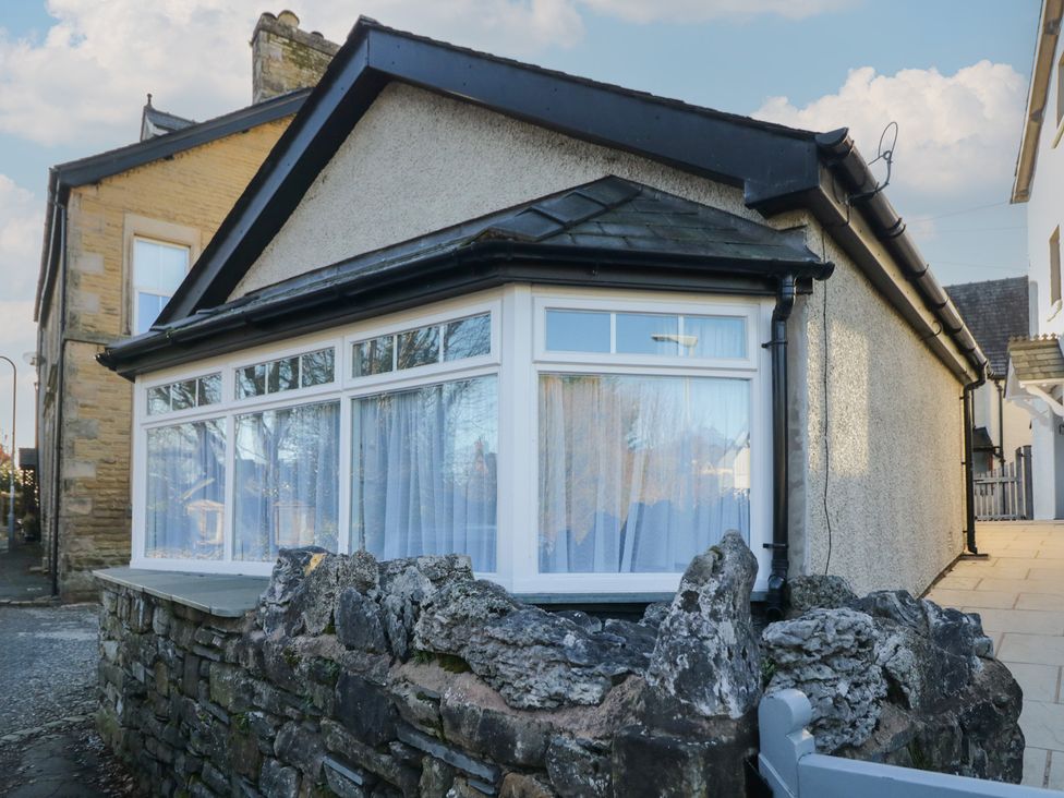 A house with large windows and a stone wall at Renes Shop in Grange-Over-Sands