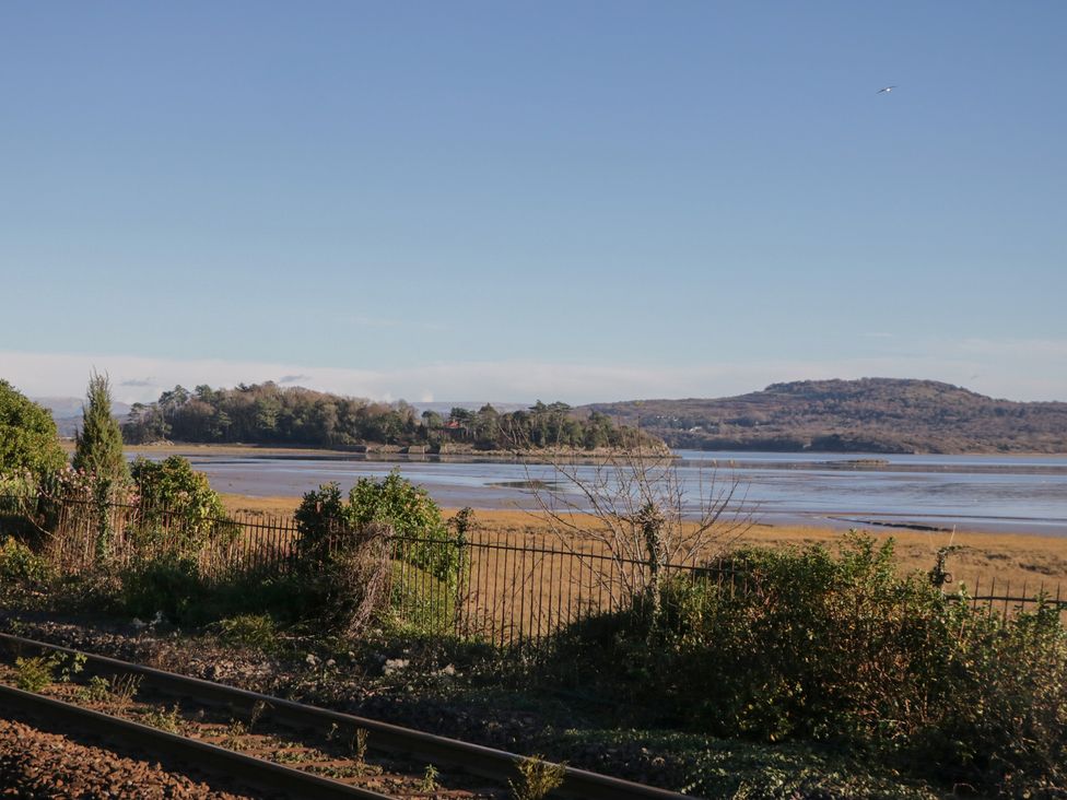 A view of water and land with trees and a fence beside train tracks at Renes Shop in Grange-Over-Sands