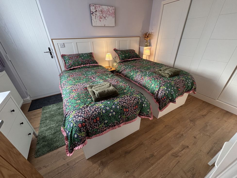 A bedroom with twin beds and a lamp at Drapers Cottage in Cark In Cartmel