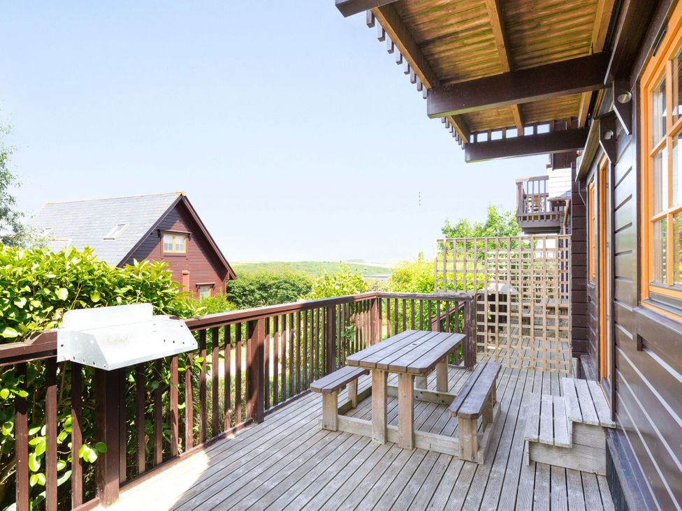 A deck with a wooden table and benches at Scandinavian Lodge 4 in Portreath