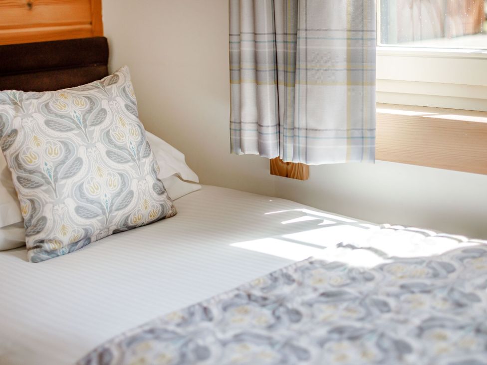 A bed with a patterned pillow and bedspread at Scandinavian Lodge 4 in Portreath