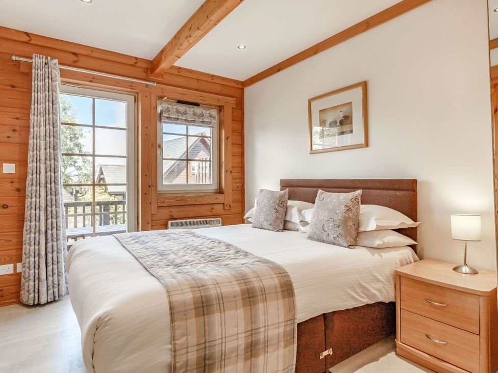 A bedroom with a bed and windows at Scandinavian Lodge 4 in Portreath