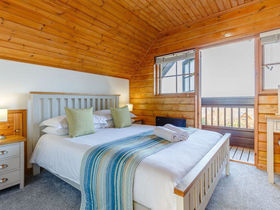 A bedroom with a bed and windows at Kinder Lodge in Portreath