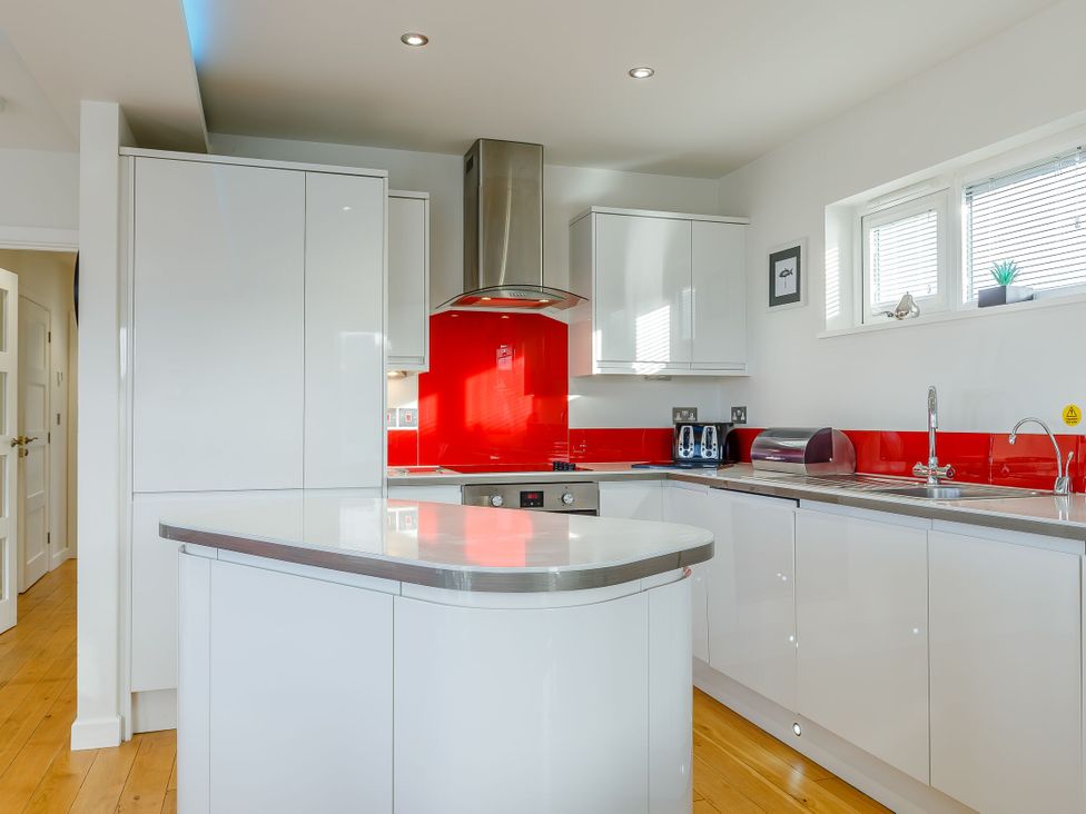 A kitchen with a red backsplash and modern appliances at Signature Lodge Pet 4 Portreath