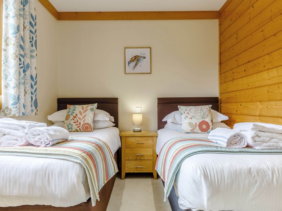 A bedroom with twin beds and a nightstand at Scandinavian Lodge 6 Portreath